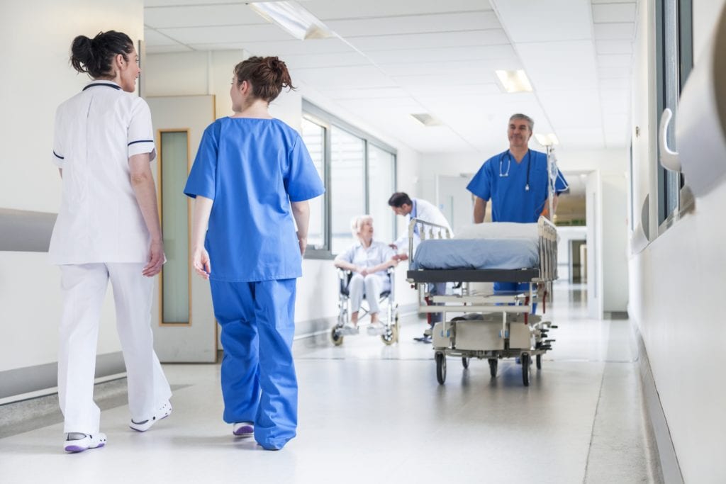 nurses walking down hallway with nurse with gurney walking other direction